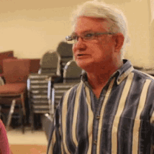 a man wearing glasses and a striped shirt is talking to someone