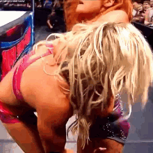 two women are wrestling in a ring and one of them is wearing a pink bikini top .