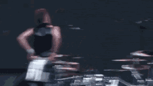a man is playing drums on a stage with a drum set in the background .