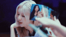 a woman with blonde hair is looking at a picture of a woman .