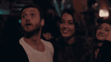 a man with a surprised look on his face stands next to a woman who is smiling