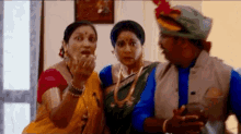a man and two women are standing next to each other in a room and talking .