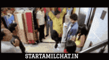 a man in a yellow shirt is hanging upside down in an elevator and the website starttamilchat.in is displayed