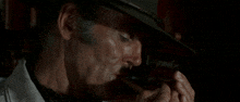 a man in a hat smoking a cigar with smoke coming out of his mouth