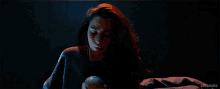 a woman in a dark room holds a lime in her hands