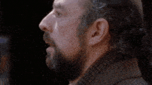 a man with a beard and a scarf around his neck looks down with his eyes closed
