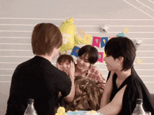 a group of people sitting around a table with balloons and a banner that says ' happy birthday ' on it