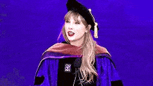 a woman in a graduation cap and gown is standing in front of a microphone on a stage .