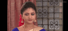 a woman in a blue and gold saree is standing in a room .
