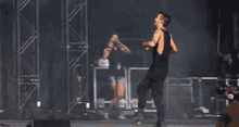 a man is standing on a stage holding a microphone and dancing .