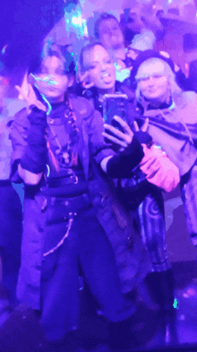 a group of people are taking a selfie in a dark room with purple lights