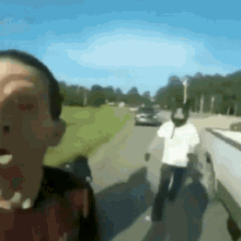 a blurry picture of a man walking down a road with a car in the background