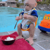 a baby monkey is sitting next to a bowl of food with a fork and knife