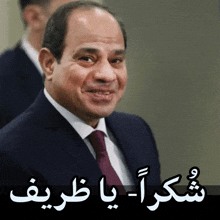 a man in a suit and tie is smiling in front of a sign in arabic