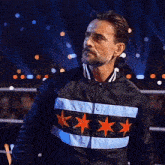 a man with a beard wearing a black jacket with chicago stars on it .