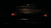 a car is driving down a road at night with its headlight on