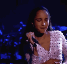 a woman is singing into a microphone while wearing a crop top .
