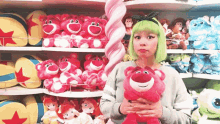 a woman with green hair is holding a stuffed animal in front of a display of stuffed animals