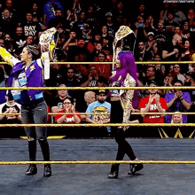 two women are standing in a wrestling ring with a crowd watching .