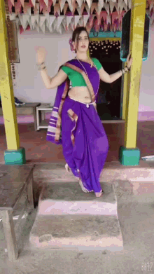 a woman in a purple saree is standing on steps