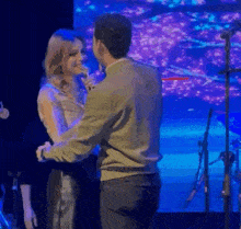 a man and woman are dancing on a stage in front of a microphone .