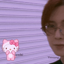 a man wearing glasses stands in front of a hello kitty sticker
