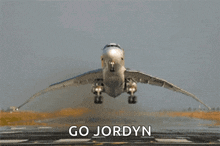 an airplane is taking off from a runway with the words " go jordyn " below it