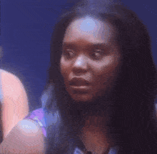 a woman with long black hair is looking at the camera with a serious look on her face .