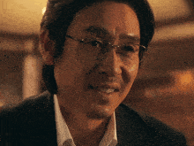 a man wearing glasses and a suit looks at the camera