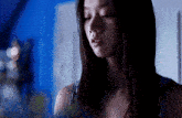 a woman in a dark room with a blue wall behind her