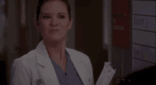 a woman in a lab coat is holding a clipboard in front of a sign that says rooms .