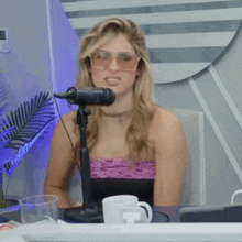 a woman is sitting in front of a microphone wearing sunglasses and a choker .