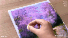 a person is painting a picture of purple flowers on a white canvas