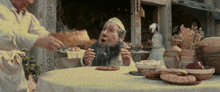 a man with a beard sits at a table with bread and popcorn