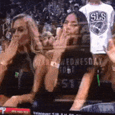 two women are sitting in a stadium watching a basketball game .