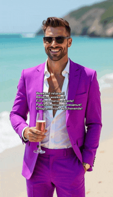 a man in a purple suit is holding a glass of champagne on the beach
