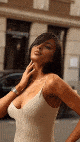 a woman in a white tank top with a plunging neckline