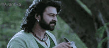 a man with a beard wearing a green shirt and a necklace with the hashtag avantika on the bottom