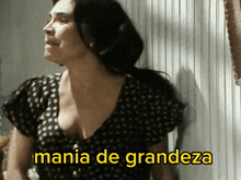 a woman in a black and white polka dot dress with the words mania de grandeza written below her