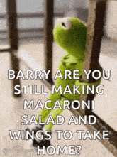 kermit the frog is sitting on a railing looking out a window .