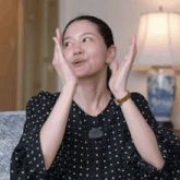 a woman wearing a black polka dot shirt is making a face