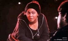 a woman wearing a beanie is talking to a man on a stage .