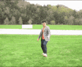 a man in a suit is walking on a grassy field