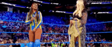 two women are standing in a wrestling ring talking to each other and laughing .