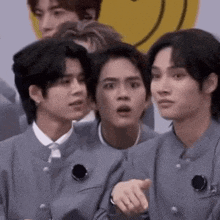 a group of young men are standing next to each other and one of them is pointing at something .