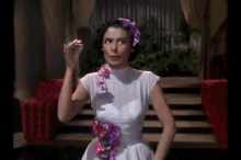 a woman in a white dress with purple flowers on the sleeves