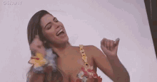 a woman in a bikini is dancing and smiling with her hands in the air .