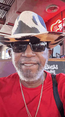 a man wearing a cowboy hat and sunglasses stands in front of a sign for blues brewery