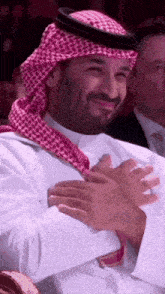 a man wearing a head scarf and a white shirt is smiling and clapping his hands