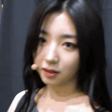 a close up of a woman 's face with long black hair and a microphone in her mouth .